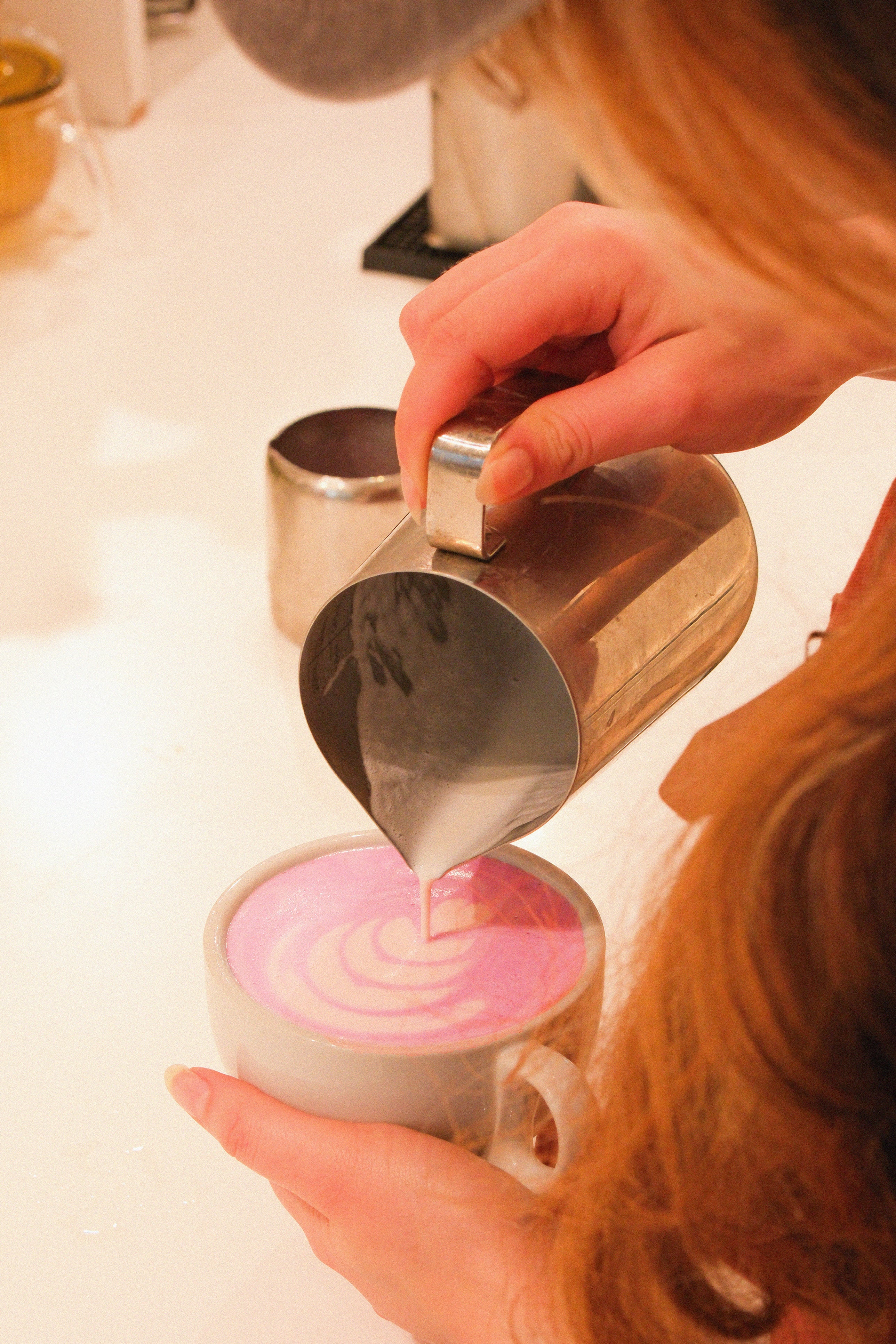 Barista versant un Ube Latte dans un verre.